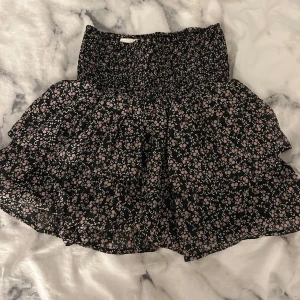 Kjol - Söt kortkjol med blommigt mönster i rosa och svart. Storlek 146 men passar xs/s där av att den är elastisk! Skriv för fler frågor eller bilder!💕