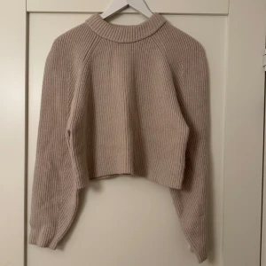 Beige stickad tröja från Carin Wester - Croppad stickad tröja med högre krage och ballongärmar. Det värmer bra och är av skönt material. Använd ett fåtal gånger men kommer tyvärr inte till användning något längre.🤎 Nypris: 349kr