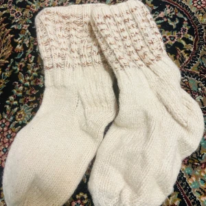 Stickade begiea strumpor - Mysiga stickade strumpor i beige med ett diskret mönster upptill. Perfekta för kalla dagar när du vill hålla fötterna varma och bekväma.