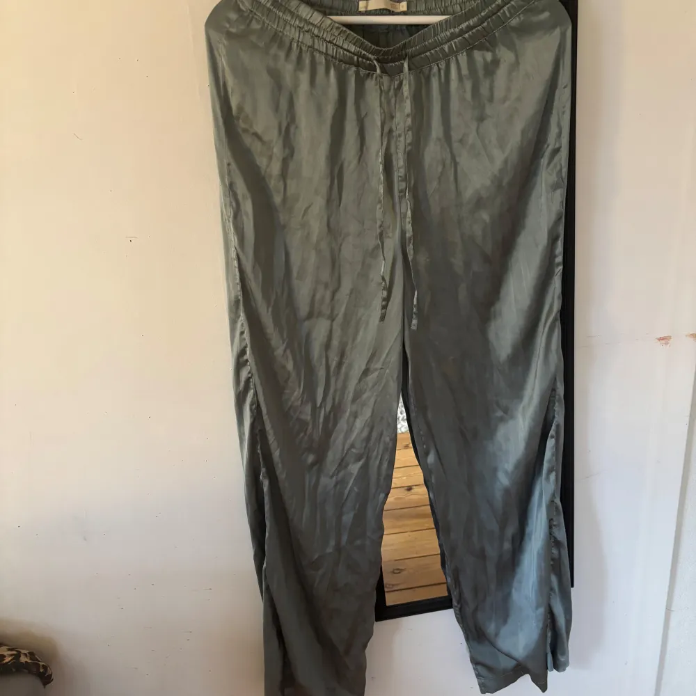 Snyggt och bekvämt pyjamassett i satinmaterial. De har en loose passform och är perfekta för en avslappnad stil. Byxorna har en elastisk midja med snörning för extra komfort.. Muu.