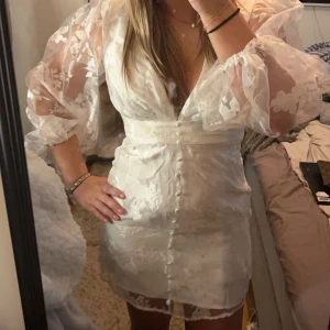 Vit kortklänning med puffärmar (STUDNETKLÄNNING)  - Säljer denna sååå snygga studentklänning! Den är verkligen så perfekt och snygg😍😍 Endast använd 1 gång! (När jag tyvärr fick hem klänning hade den två små hål, men verkligen inget man ser eller tänker på) nypris: 1500