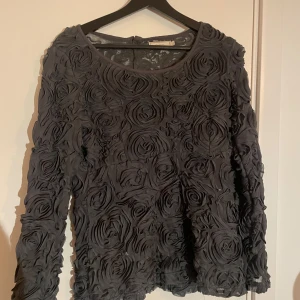 grå blommig tröja med rosdetaljer - Unik grå tröja med vackra rosdetaljer över hela ytan. Tröjan har långa ärmar och en rund halsringning, perfekt för att ge en elegant touch till din outfit.