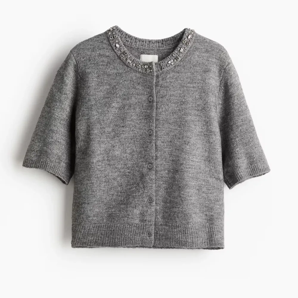 Aldrig använd grå kofta från H&M med korta ärmar och pärldetaljer runt halsen.  Koftan har knappar framtill och ribbade kanter. Storlek M men passar Xs/S. Skriv för fler bilder❤️. Neuletakit & Villapaidat.