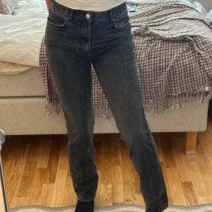 Svarta jeans med hög midja - Snygga svarta jeans med hög midja och klassisk femficksdesign. De har en rak passform och stängs med knapp och dragkedja. Perfekta för en stilren look.