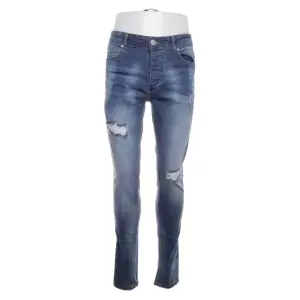 Snygga blå jeans från boohooMAN med slitna detaljer och en modern skinny passform. De har en klassisk femficksdesign och stängs med dragkedja och knapp. Perfekta för en trendig look.