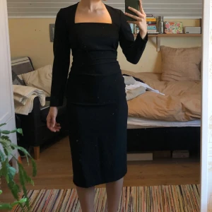 Svart klänning från Zara - Säljer denna eleganta svarta klänning från Zara med långärmad design och fyrkantig urringning. Klänningen är indragen i både ryggen och sidorna som ger den en tight passform och den perfekta stilrena looken. Använd endast en gång, så är i nyskick. Köpte den för några år sedan, så den finns inte kvar i butik. Nypris: 700kr