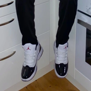 Nike Air Jordans i svart och vit - Snygga Nike Air Jordans i svart och vit med klassisk design. Skorna har en hög snörning och en röd logotyp på plösen. Perfekta för dig som vill ha en stilren look med en sportig touch. Änvänder knappt.