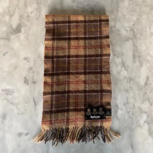 Barbour halsduk  - Skick: 8/10. Halsduken är i bra skick och har inga defekter. Från märket Barbour. Längd: 148cm x 23cm