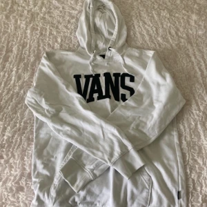 Vit hoodie från Vans - Säljer en stilren vit hoodie från Vans med deras ikoniska logga tryckt på framsidan. Hoodien har en klassisk design med känguruficka och justerbar huva. Perfekt för en avslappnad stil. 🏂
