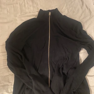 Svart tröja med dragkedja - Snygg svart tröja med dragkedja och hög krage. Perfekt för kyligare dagar. Tröjan har långa ärmar och ribbade muddar vid ärmslut och nederkant.