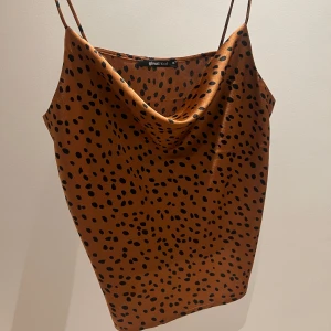 Topp  - Snygg brun linnetopp från Gina Tricot med svarta prickar. Toppen har tunna justerbara axelband 