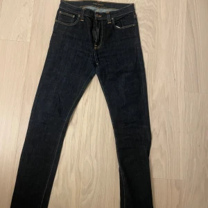 Mörkblå jeans från Nudie Jeans - Snygga mörkblå jeans från Nudie Jeans med en tight passform. De har klassisk femficksdesign och kontrasterande sömmar. Perfekta för en stilren look.
