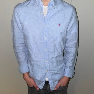 Morris skjorta - Snygg ljusblå skjorta i linne från Morris med broderad detalj på bröstet. Skjortan har långa ärmar och knappar framtill. Perfekt för en stilren look! 100 % linne