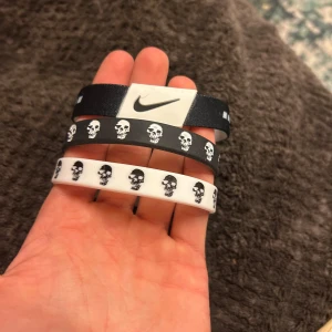 Svarta och vita armband med dödskallar från Nike - Snygga armband från Nike i svart och vitt med dödskallemönster. Ett av armbanden har texten 'JUST DO IT.' i vitt. Perfekt accessoar för en cool look.