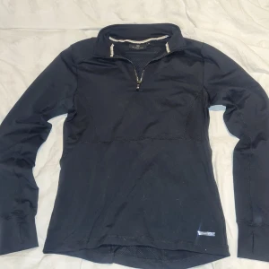 Svart tröja från H Collection - Säljer en svart tröja från H Collection med dragkedja och tumhål vid ärmsluten. Perfekt för en sportig look eller en avslappnad dag. Tröjan har en hög krage och är tillverkad i ett mjukt material. Den är köpt på Hööks så det ska vara en rid tröja men går att använda till andra saker med. Den är är använd en gång så den har vart nära hästar så om ni har några allergier skriv och fråga bara! 