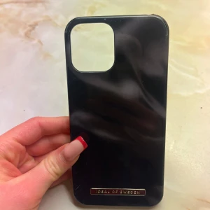 Svart mobilskal från Ideal of Sweden - Snyggt svart mobilskal från Ideal of Sweden. Skalet har en stilren design med en metallisk logotypdetalj. Perfekt för att ge din mobil en elegant look. Har som sagt lite defekter och nån enstaka repa men inget som hindrar funktionen och utseende mässigt! Hör av er vid intresse💕