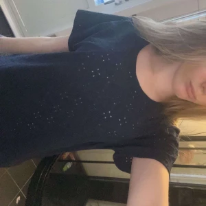 Mörkblå topp från Isolde - Säljer en mörkblå topp från Isolde med ett diskret hålmönster. Toppen har korta ärmar och en rund halsringning. Perfekt för en stilren look. Använd flertal gånger men inga märkbara tecken på det.