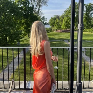 Orange långklänning i satin med öppen rygg - Elegant orange långklänning i satin med ärmlös design och öppen rygg. Perfekt för sommarens festligheter. Klänningen har en vacker glans och en smickrande passform. Klänningen är från Mango och är köpt förra året inför min egna bal, lappen är bortklippt men är i storlek 36💕💕