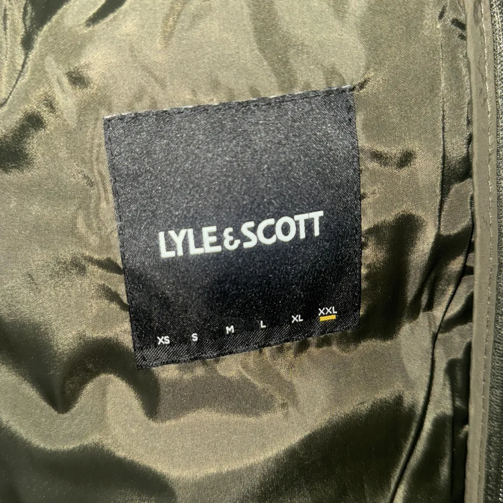 Säljer en olivgrön pufferjacka från Lyle & Scott med dragkedja och huva. Jackan har ett broderat emblem på bröstet och är perfekt för kyligare dagar. Den är långärmad och quiltad för extra värme. Passar bra för både höst och vinter. Har använts 2 gånger bara. Takit.