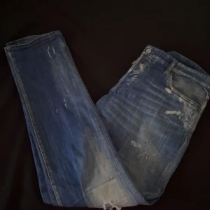 Blå jeans från Dsquared2 - Snygga blå jeans från Dsquared2 med en cool slitningseffekt. De har en klassisk femficksdesign och en knappgylf. Perfekta för en avslappnad stil med en touch av edge.
