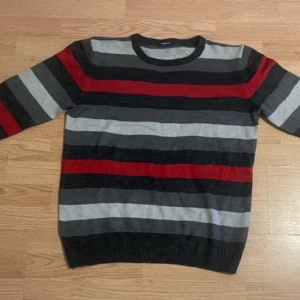 Randig tröja från LC Waikiki - Säljer en randig tröja från LC Waikiki i svart, grått och rött. Tröjan har långa ärmar och en rund halsringning. Perfekt för en avslappnad stil.