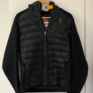 Svart jacka från Parajumpers - Säljer en svart jacka från Parajumper med dragkedja och quiltad design. Jackan har långa ärmar och en praktisk huva vilket är perfekt inför våren. Säljer jackan billigt pågrund av att det är två små hål på undersidan av vänster ärmen men det är inget man märker. Pris kan diskuteras vid snabb affär, nypris:4500kr