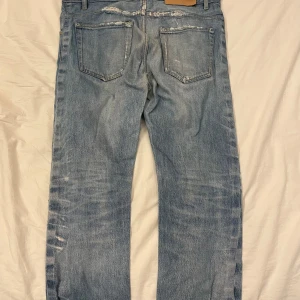 Blå jeansbyxor storlek W30 L34 - Säljer ett par klassiska blå jeansbyxor med en avslappnad passform. Byxorna har en sliten look med flera distinkta slitningar och en knappgylf. Perfekta för en casual stil. Jag själv är 174 och dom var lite förstora. Pris kan diskuteras!