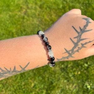 Svart och transparent pärlarmband - Säljer ett snyggt armband med svarta och transparenta pärlor. Armbandet är elastiskt och passar perfekt för både vardag och fest. Det har en stilren design som gör det lätt att matcha med andra smycken.