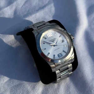 Silverfärgad klocka från Longines - Säljer en stilren och elegant silverfärgad klocka från Longines. Klockan har en klassisk design med en vit urtavla och tydliga siffror. Armbandet är i rostfritt stål och har en robust känsla. Perfekt för både vardag och fest! Kom PM för specifikation