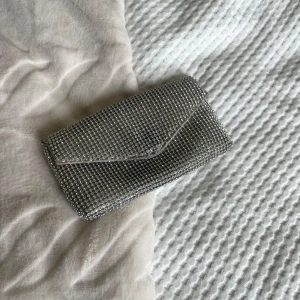 Supersnygg glittrig väska - En miniväska i glitter perfekt för fest eller utgång! 😍 Väskan har krokar där man kan sätta fast ett axelband om man vill! Använt skick men det syns inte på utsidan! 🩷