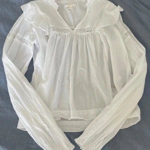Vit blus - Säljer en superfin vit blus från Gina Tricot. Den har långa ärmar och vackra volangdetaljer vid axlarna och runt halsen. Blusen är gjord i ett lätt och luftigt material. Passar både till vardags och till fest. Helt oanvänd. 