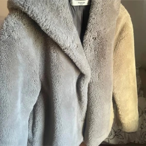 teddyjacka från Mango - Supermysig teddyjacka från Mango som är perfekt för kyliga dagar. Den har en mjuk och fluffig yta med en klassisk krage och knäppning framtill. Jackan är långärmad och ger en riktigt cozy vibe. Perfekt för både höst och vinter!