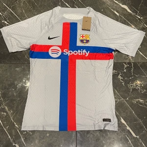 F.C Barcelona tredjeställ 2022/23 - F.C Barcelona tredjeställ 2022/23 Strl: XXL, men passar L/XL Playerversion dvs. Mindre i strl. Ny med tagg på! 