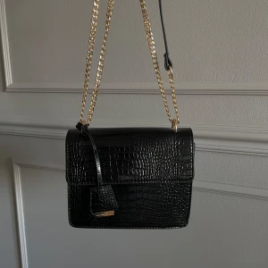 Handväska - Fin svart handväska från nelly med gulddetaljer, använd en gång 🖤