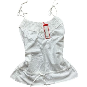 Vit topp från Esprit med spetsdetaljer - Säljer en söt vit ärmlös topp från Esprit med smala axelband som knyts. Toppen har fina spetsdetaljer upptill och en lätt rynkad effekt. Den har även lite resår i toppen baktill. Toppen är helt ny med prislapp kvar. Nypris: 399 Storlek: 38