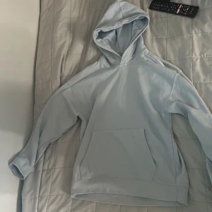 Hoodie  - Ljus blå hoodie från zara med en ficka på magen, storlek 152 