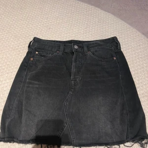 Svart jeanskjol - Säljer en snygg svart jeanskjol. Den har en klassisk femficksdesign och en rå kant längst ner som ger en cool och avslappnad look. Perfekt för både vardag och fest! 🖤