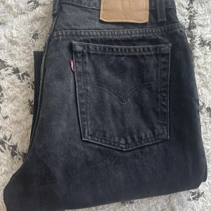 Svarta jeans från Levis - Säljer ett par svarta jeans från Levis. De är i bra skick och har en klassisk femficksdesign. Jeansen har rak passform. midjan medel highwaist, storlek står ej. men passar mig som är en 38. Jeansbenen går ända ned till fötterna.