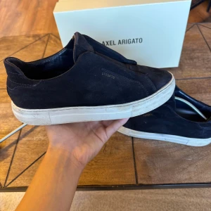 Svarta sneakers från Axel Arigato - Säljer ett par sjysta skor från Axel Arigato. De är i mocka. Skorna är i använt skick men utan några defekter. köpta för 2500kr och säljs endast för 890! priset kan diskuteras vid snabb affär