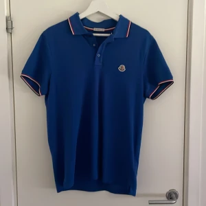 Moncler piké  - Säljer nu den här sjukt snygga moncler piken i en riktigt snygg blå kvitto finns!!, självklart äkta vilket man kan se på tagsen i piken!, den är i storlek m. Och är ej andvänd sen jag köpte den!, om ni har några frågor är det bara att fråga på!! Mvh!