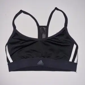 Säljer en svart sport-bh från Adidas. Den är perfekt för träning. Materialet är syntet och den har en stilren design med Adidas-loggan på framsidan. Den har också en öppen rygg med smala axelband för extra komfort.