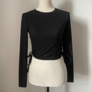 Svart långärmad tröja - Svart långärmad tröja från Zara! I ribbat material och med reglerbara snören längs sidorna (går att ljustera hur kort man vill bära) Storlek S 🖤