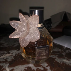 Flowerbomb parfym från Viktor & Rolf - Säljer en elegant (nästan full) LIMITED EDITION GLITTER Flowerbomb parfym från Viktor & Rolf. Flaskan är facetterad och har en vacker blomma som dekoration. Parfymen har en varm och blommig doft, perfekt för den som älskar en lyxig känsla. Nypris för flaskan är ca 1000kr. Jag säljer flaskan för 400kr. Köparen står för frakten.