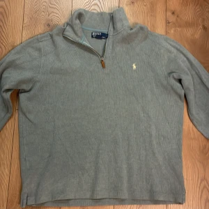 Blå tröja med dragkedja från Polo Ralph Lauren - Säljer en stilren blå Baggy tröja från Polo Ralph Lauren med halv dragkedja och broderad logotyp på bröstet. Perfekt för en avslappnad och snygg look. Tröjan har långa ärmar och är tillverkad i ett mjukt material.