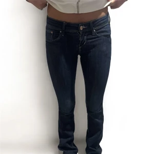Low rise jeans - Snygga mörkblå jeans med en klassisk design. De har en normal passform och är perfekta för en avslappnad stil. Jeansen har fickor både fram och bak samt en knapp- och dragkedjestängning. Midjemått: 33cm, innerbenslängd: 78cm och grenmått: 16cm.