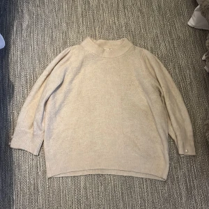 Beige stickad tröja från ICHI - Säljer en mysig beige stickad tröja från ICHI. Tröjan har medel långa armar och fina pärldetaljer vid ärmsluten. Perfekt för kyliga dagar och ger en stilren look. Passar bra till både jeans och kjol. 🧶✨