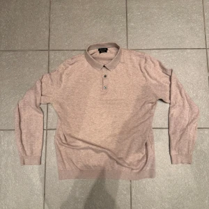 Beige rugbytröja från Massimo Dutti - Säljer en stilren beige rugbytröja från Massimo Dutti. Tröjan har långa ärmar och tre knappar framtill. Perfekt för en avslappnad men ändå elegant look. 