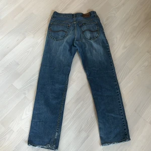 Blå jeans från Lee - Säljer ett par klassiska blå jeans från Lee med rak passform. De har en dragkedja och knapp framtill samt fem fickor. Perfekta för en avslappnad stil. Byxorna känns lite mindre i midjan än vad det är! 