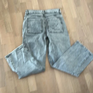 Grå jeans från Calvin Klein - Snygga grå jeans från Calvin Klein med en klassisk design. De har en rak passform och är tillverkade i ett slitstarkt denimtyg. Perfekta för en avslappnad stil.