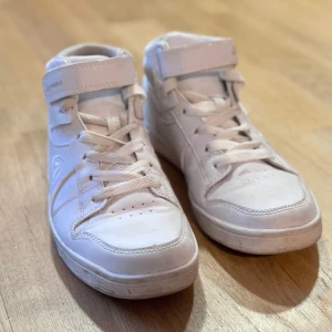 Vita sneakers från Firefly - Snygga vita sneakers från Firefly med snörning och kardborreband. Skorna har en högre modell med vadderad ankel för extra komfort. Perfekta för en avslappnad stil.